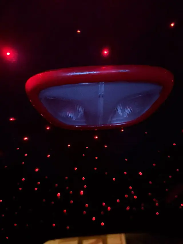 Red suede starlight headliner fitted by Rook Auto Customs, fibre optic stars lit across the roof beside the dome light
