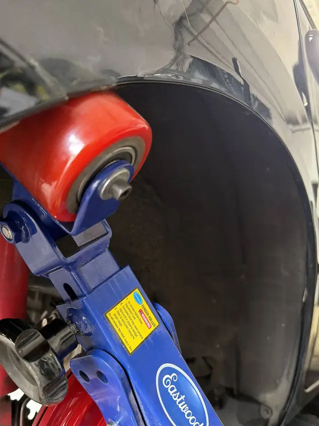 Fender-rolling tool in use on a vehicle's wheel well