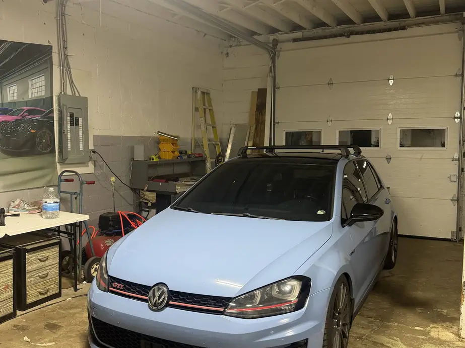 Light blue wrapped Volkswagen Golf GTI wagon parked inside the Rook Auto Customs shop bay