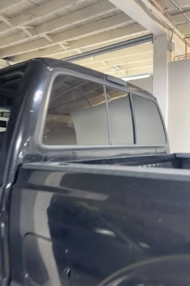 Tint film being worked onto the rear window of a truck cap at Rook Auto Customs